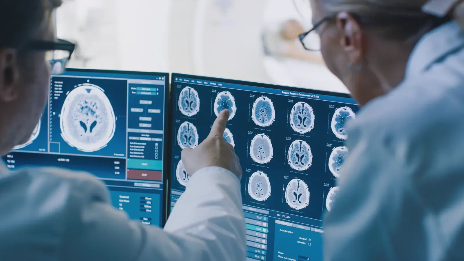 Two clinicians reviewing a set of brain scans on screen